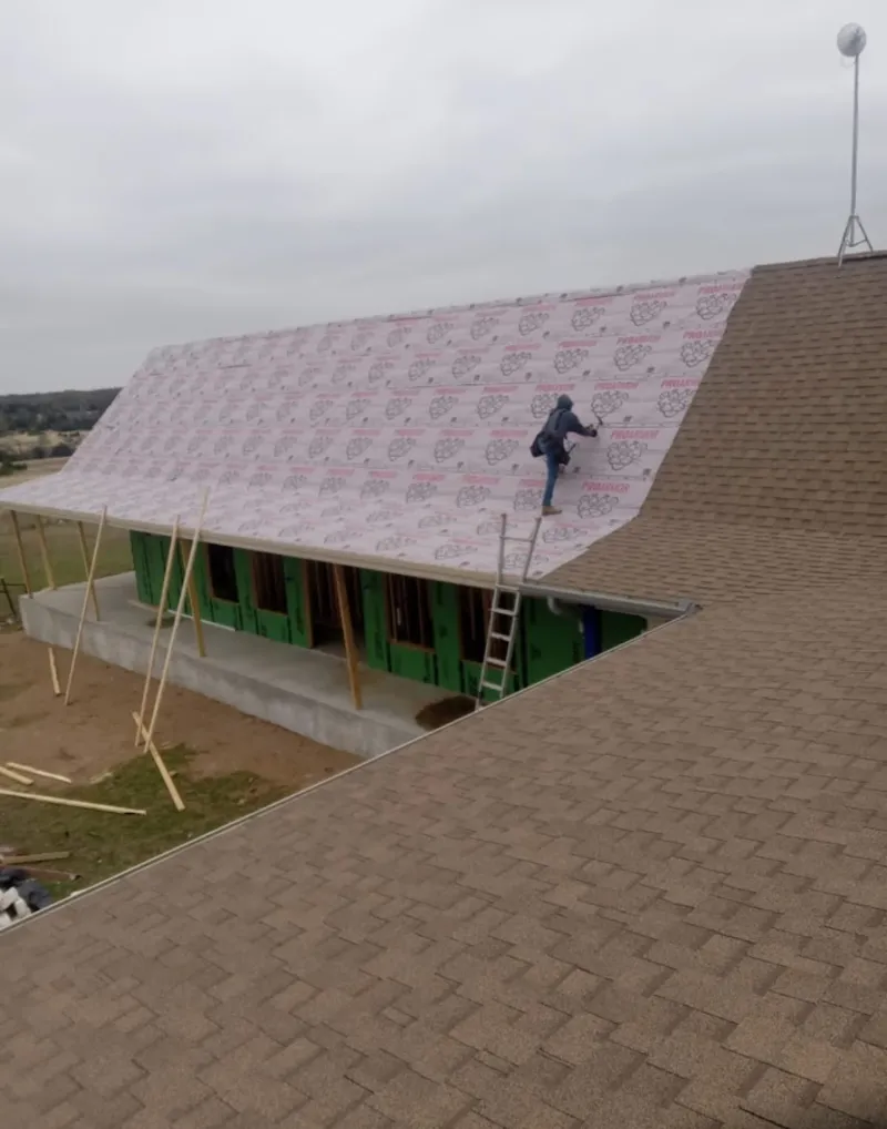 Worker preparing underlayment for a metal roof installation in Fulton